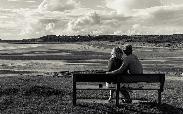 Couple assis sur un banc devant le bord de mer.